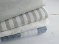 Pile of striped white grey blue linen cotton fabrics on white background.