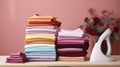 Pile of t-shirts and sweaters on wooden ironing board. Neat stack of clean freshly laundered clothes and electric iron on Royalty Free Stock Photo