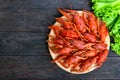 A pile of tasty boiled crawfish on a round wooden tray on a dark table. Top view. Royalty Free Stock Photo