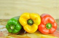 Pile of three different kinds of bell peppers on a wood background