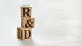 Pile with three wooden cubes - letters R&D meaning Research and Development on them, space for more text / images at right side
