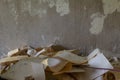 A pile of torn off wallpaper on a background of a concrete wall Repair, removal of old wallpaper