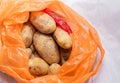 A pile of unwashed potatoes lies in a bag
