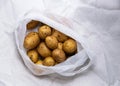 A pile of unwashed potatoes lies in a bag