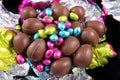 Pile of unwrapped chocolate easter eggs with the colorful foil wrapping surrounding it on a black background Royalty Free Stock Photo