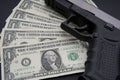 Pile of US dollar cash and a black pistol gun. Royalty Free Stock Photo