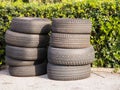 Pile of used worn out tyres green bushes in background