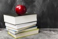 Pile of various books and red apple on dark background. Copy spa Royalty Free Stock Photo