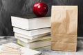 Pile of various books, red apple and package of lunch on dark ba Royalty Free Stock Photo