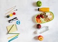 A pile of various stationery on table, notepad, colored pencils, ruler, marker, planer, space for text. Delicious school lunch box