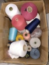 A pile of various threads in a cardboard box