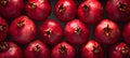 A stack of red, seedless pomegranates on a table a staple food and superfood