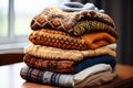 Pile of warm knitted sweaters on wooden table. Warm wool clothes stack. Autumn or winter fashion style. Cozy season concept Royalty Free Stock Photo