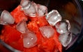 A pile of watermelon fruit cuts into small pieces with ice cubes and sugar inside an electric blender ready to be blended