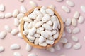 Pile of white beans in wooden bowl on pastel pink background Royalty Free Stock Photo