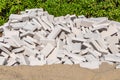 Pile of white bricks is on the yellow sand on the green plants background Royalty Free Stock Photo