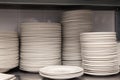 A pile of white clean ceramic porcelain plates on a metal rack in the back of the restaurant. Concept of preparation for banquet, Royalty Free Stock Photo