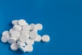 Pile of white medical pills lies on a blue background. pharmaceutical concept