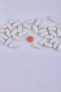 Pile of white medical pills and one colorful pill on white background. Royalty Free Stock Photo