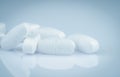 Pile of white oblong tablets pills on gradient background. White antibiotic tablet pills. Pharmaceutical industry. Pharmacy