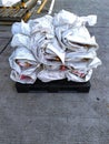 Pile of white paper bags tied and placed on a black wooden pallet Royalty Free Stock Photo