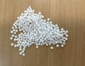 a pile of white pellets on a wooden table, production of plastic parts, plastic injection, a bunch of plastic pelets, plastic Royalty Free Stock Photo