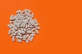 Pile of white pills on orange background with copy space. The upper angle of view. The concept of dietary supplements