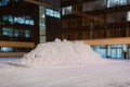Pile of white snow in front of a office building. Huge heap of white street snow in the city at night