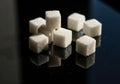 Pile of white sugar cubes on a dark reflective surface Royalty Free Stock Photo