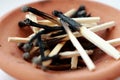 Pile of wooden burnt matches in brown clay plate. Matches close up.
