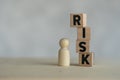 Pile wooden cubes of RISK text placed near wooden figures peg doll, Risk assessment, decision to accept business result in Royalty Free Stock Photo