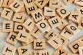 Pile of wooden tiles with various letters scattered on white stone like board, closeup view from above