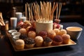 a pile of wooden toothpicks alongside a tray of bite-sized desserts