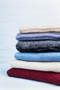 Pile of wool sweaters and knitted winter clothes on blue wooden background. Copy space for text. Royalty Free Stock Photo