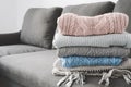 Pile of woolen sweaters on gray sofa in living room