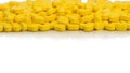 Pile of yellow ovoid-rectangular shape tablet pills on white background with copy space. medicine for relief pain.