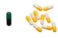 Pile of yellow and white capsules and one bigger green and black capsule Royalty Free Stock Photo