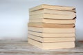 Pile of yellowed old used paperback books on wood desk and light blue background