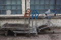 Piled dirty rusty weathered cargo trolleys and standing outside on a soviet blue glass bricks windows background