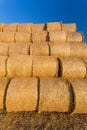 Piled hay bales on a field against blue sky Royalty Free Stock Photo