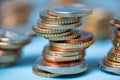 Piled up euro coins to towers. Coins on blue background. EUR currency from European Union