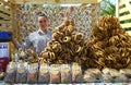 Piles of bagels and cookies placed on a counter of a stall, female seller standing behind