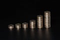 Piles of coins of different height on black background