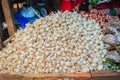 Piles of garlic bulbs are in sell offer at outdoor market place. Bunch of garlic selling in the market.