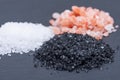 Piles of Hawaiian Black Lava Sea Salt, Coarse White Sea Salt and Himalayan Pink Salt on dark