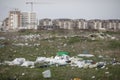 Piles of industrial and home waste lay on a field near inhabited blovks of flats