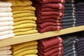 Piles of multicolored clothes on the shelves in store