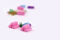 Piles of pink tablets and colored capsules