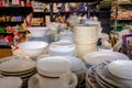 Piles of plates, crockery and ceramics on shelves in charity shop