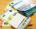Piles of wrapped Euro bills on a pine desk Royalty Free Stock Photo